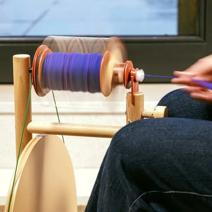 Lojan Buddy Spinnrad im Einsatz mit laufender Spule und violettem Garn, Detailaufnahme beim Spinnen mit Hand und Fuß